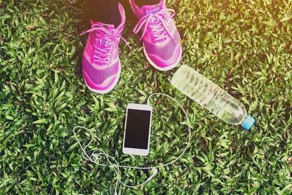 女赛跑者与智能手机和水瓶在草 — 图库照片