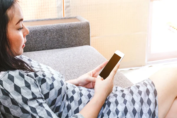 Woman using smartphone on sofa