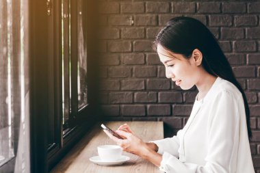 Kafede akıllı telefon kullanan bir kadın.