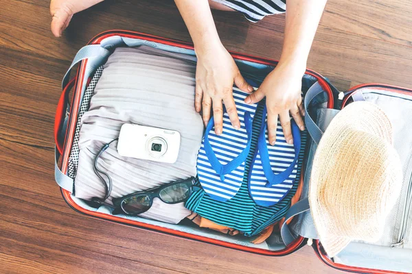 Woman packing a luggage on wooden floor