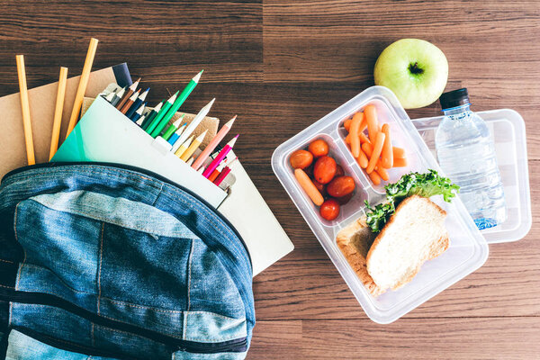 Обеденная коробка с овощами и ломтиком хлеба для здорового школьного обеда на деревянном столе
