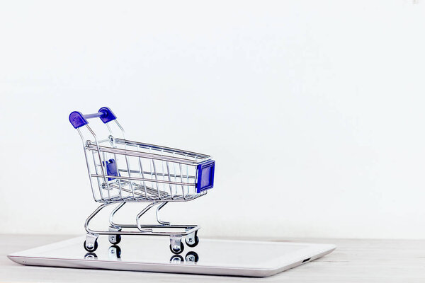 Shopping cart and tablet on wooden table - Online shopping concept