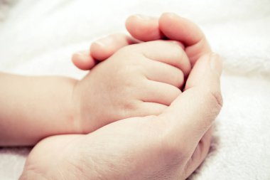 Bir bebeğin elini tutarak anne