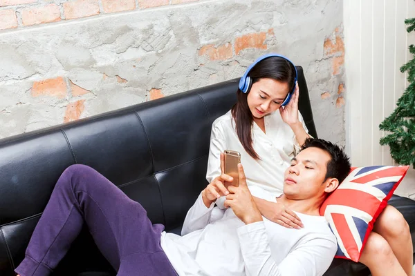 Young couple relaxing with smartphone on the sofa couch