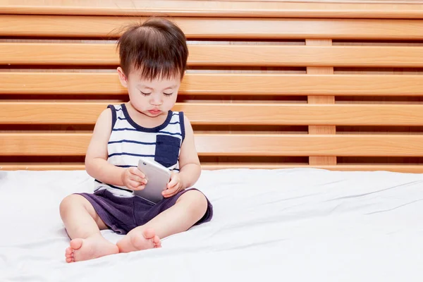 Junge Hält Smartphone Auf Bett — Stockfoto