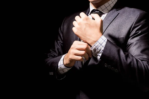 黒の背景に彼のスーツを調整するビジネスマン — ストック写真