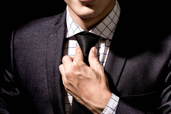 黒の背景に彼のスーツを調整するビジネスマン — ストック写真