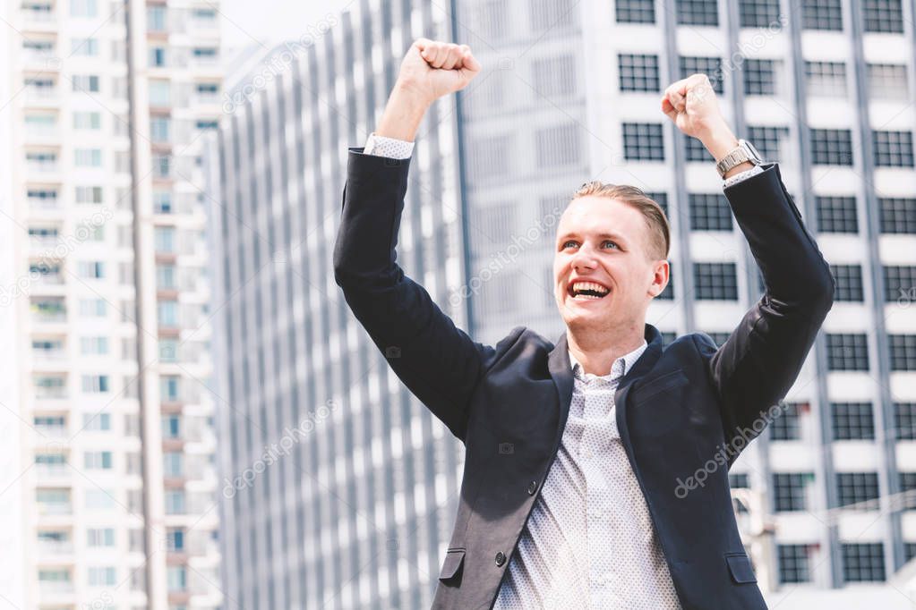 Successful businessman celebrating with arms up