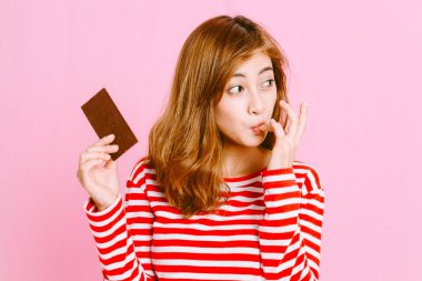 Güzel kadın, pembe arka plan koyu çikolata yeme