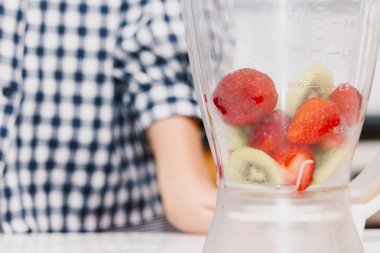 Kadın ile kitchen.healthy yaşam tarzı kavramı karıştırıcıda meyve yüzlü yapma