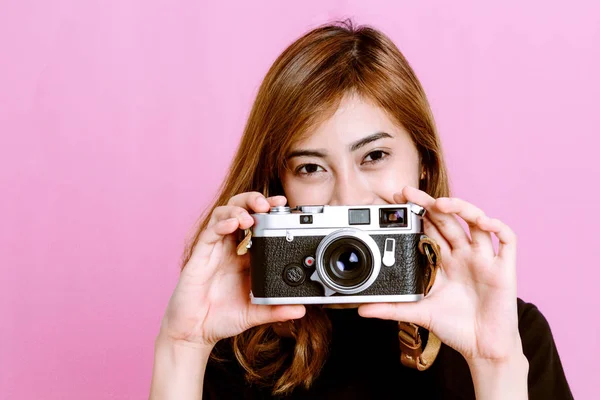 时尚照片的年轻女孩摆在手上的老式相机粉红色背景 — 图库照片