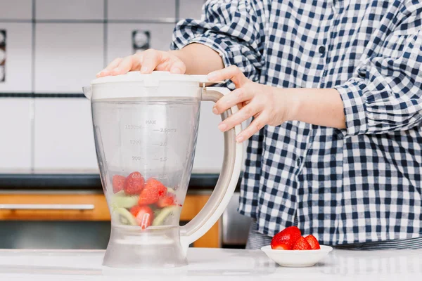 Woman making fruit smoothie with blender in kitchen.healthy lifestyle concept