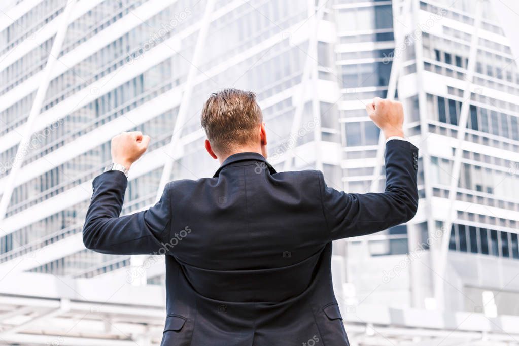 Successful businessman celebrating with arms up