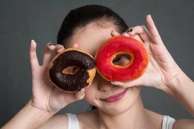 Kalori bombası çörek gri arka plan üzerinde tutan kadın. Abur cubur kavramı