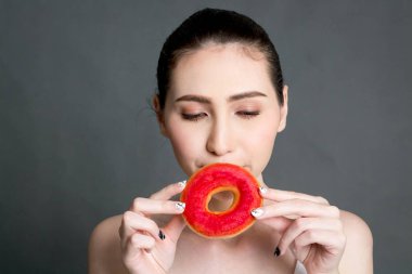 Kalori bombası çörek gri arka plan üzerinde tutan kadın. Abur cubur kavramı