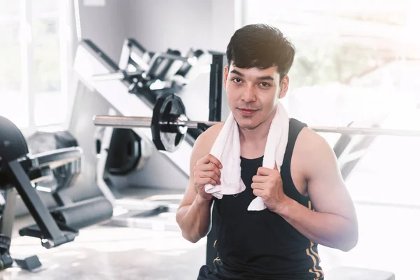 Handsome sports man standing with towel at the gym