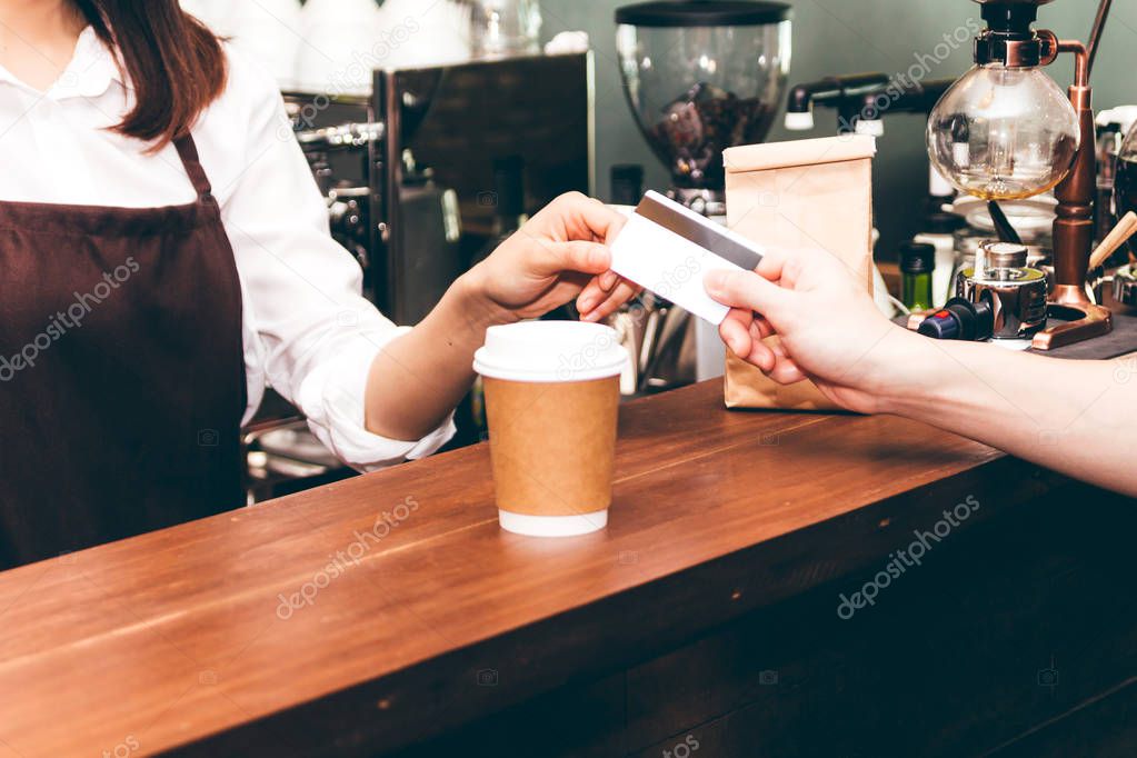 Female barista  taking a credit card from customer in coffee shop