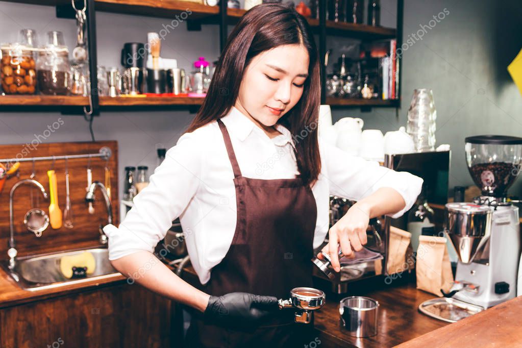 Barista using tamper to makes coffees in coffee bar