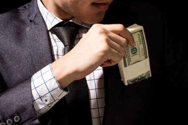 Businessman putting dollar banknotes into pocket clipart