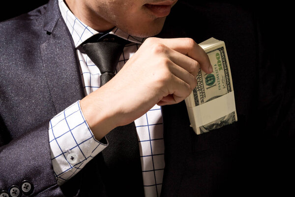 Businessman putting dollar banknotes into pocket