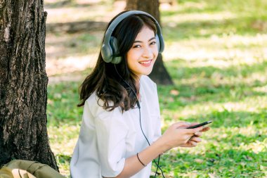 Kadın dinlenmek ve çim parkta oturan smartphone kullanın