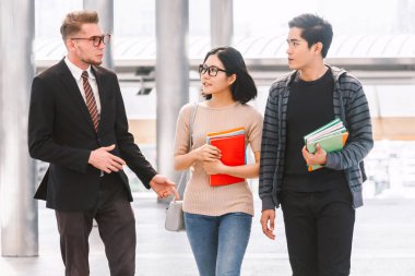 Notebook açık havada tutan iki öğrenci ile öğretmen. Eğitim kavramı