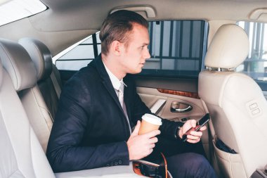 Yakışıklı işadamı bir arabanın arka koltuğunda oturan