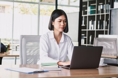 İş kadını ofiste dizüstü bilgisayar ve işletme belgesi üzerinde çalışma