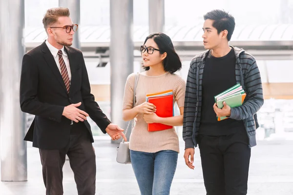 Notebook açık havada tutan iki öğrenci ile öğretmen. Eğitim kavramı