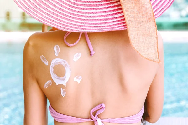 女性の背中に描かれた太陽と Suncream を適用するリゾート スパのプールで — ストック写真