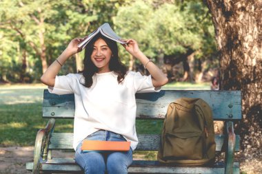 Öğrenciler genç kadın dinlenmek ve parkta bir kitap okuma