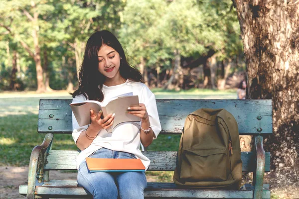 若い女性がリラックスして生徒と公園で本を読んで — ストック写真