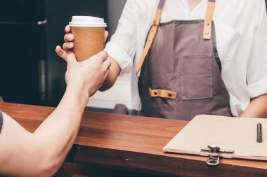Müşteri kafede kahve fincanı veren kadın barista