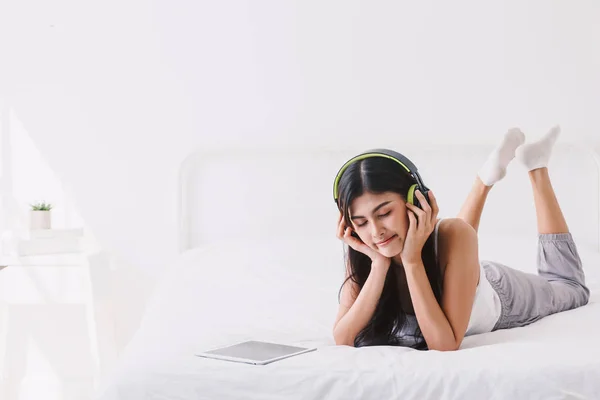 女性のベッドの上のヘッドフォンで音楽を聴く — ストック写真