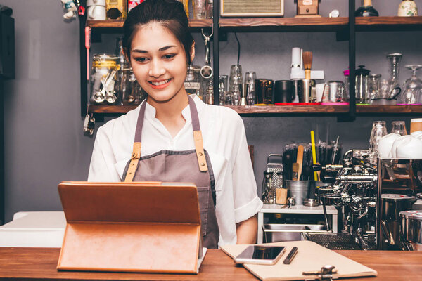 Barista woman using digital tablet compute in coffee shop counter bar