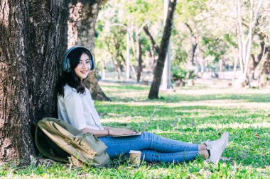 Kadın dinlenmek ve Park çimenlerin üzerinde oturan bir dizüstü bilgisayar kullanarak
