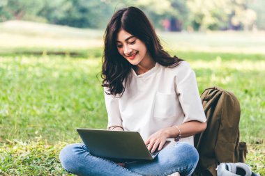 Kadın sakin Park çimenlerin üzerinde oturan dizüstü bilgisayar ile