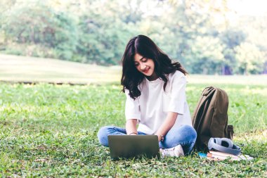 Kadın sakin Park çimenlerin üzerinde oturan dizüstü bilgisayar ile