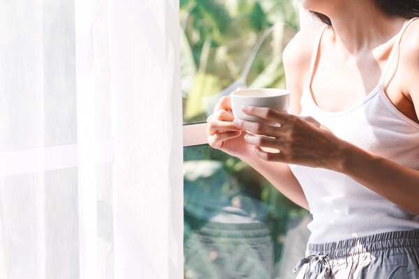 Woman drinking coffee in bedroom in the morning