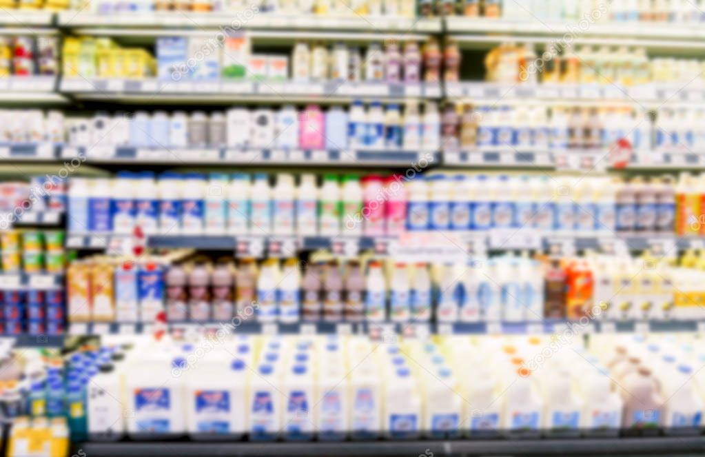 Defocused blur of Row of fresh milk bottles on fridge shelf in supermarket