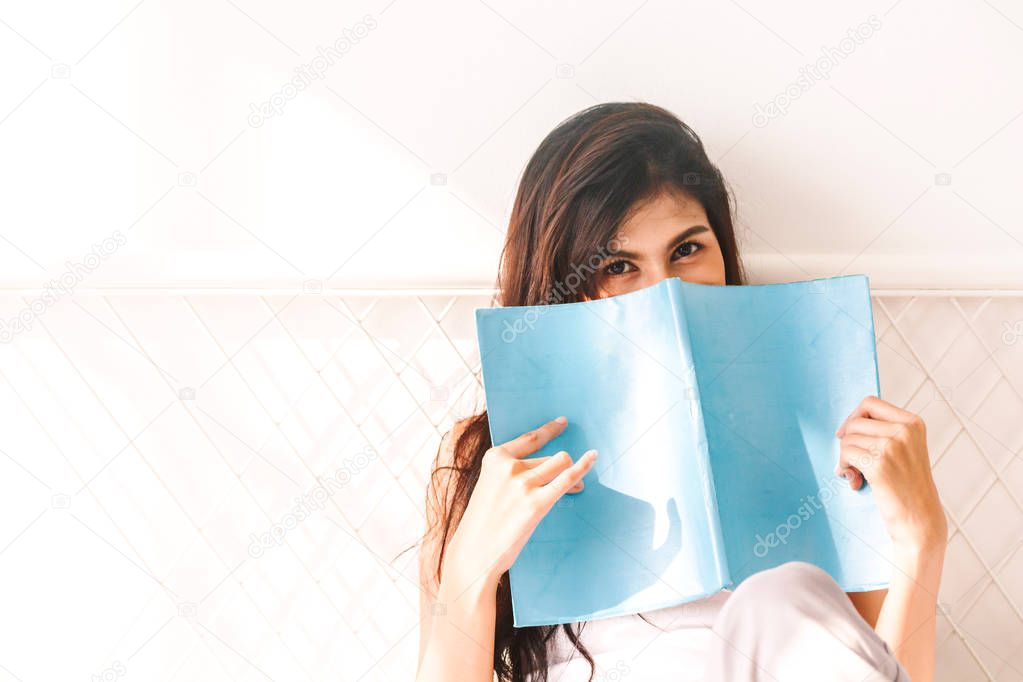 Woman reading book on bed in the morning
