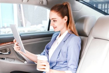 İş kadını işe geri dokunmatik tablet bilgisayar ile lüks araba koltuğunda