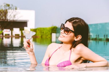 Yüzme havuzunda yaz tatile rahatlatıcı resort spa adlı kokteyl içme bikini giyen kadın
