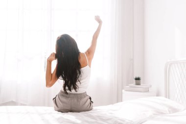 Kadın uyandıktan sonra yatakta geriniyor.