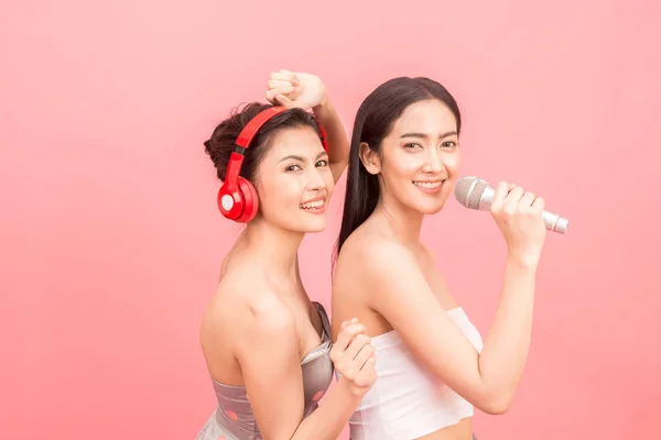 Szczęśliwy Dwóch Kobiet Śpiewając Mikrofony Różowym Tle — Zdjęcie stockowe