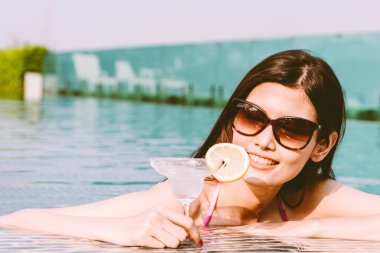 Yüzme havuzunda yaz tatile rahatlatıcı resort spa adlı kokteyl içme bikini giyen kadın