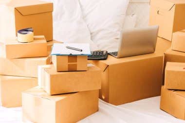 Karton kutu ve dizüstü bilgisayar yatakta yığını. İş online ve teslimat kavramı