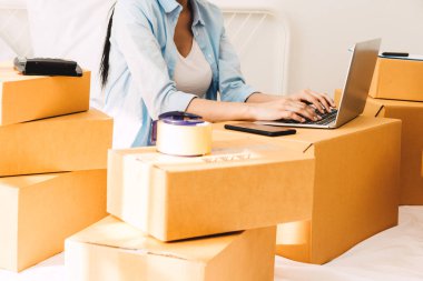 Genç kadın çalışma ve kullanım dizüstü bilgisayar ile karton kutu yatağa evde - online iş ve teslimat kavramı