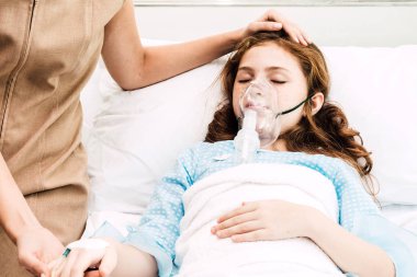 Küçük kız elini IV salin ile hastanede intravenöz tutarak anne