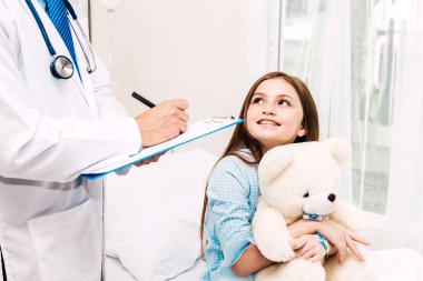 Danışmanlık doktor ve hastanede küçük kızla bilgilerini kontrol edin. Küçük bir kız sick.healthcare ve tıp vardır